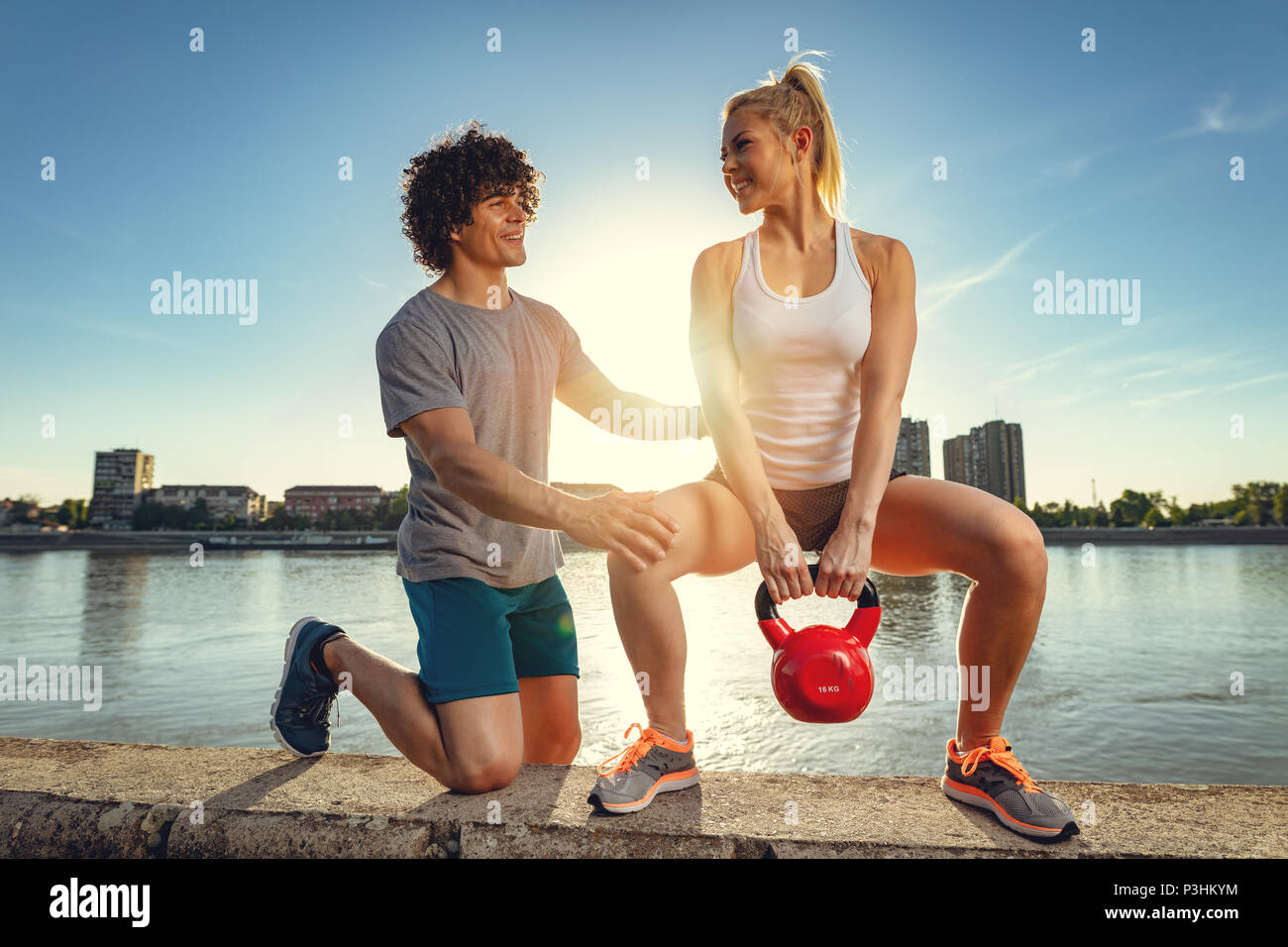 Young fitness couple doing workout with kettlebell on the wall by the ...