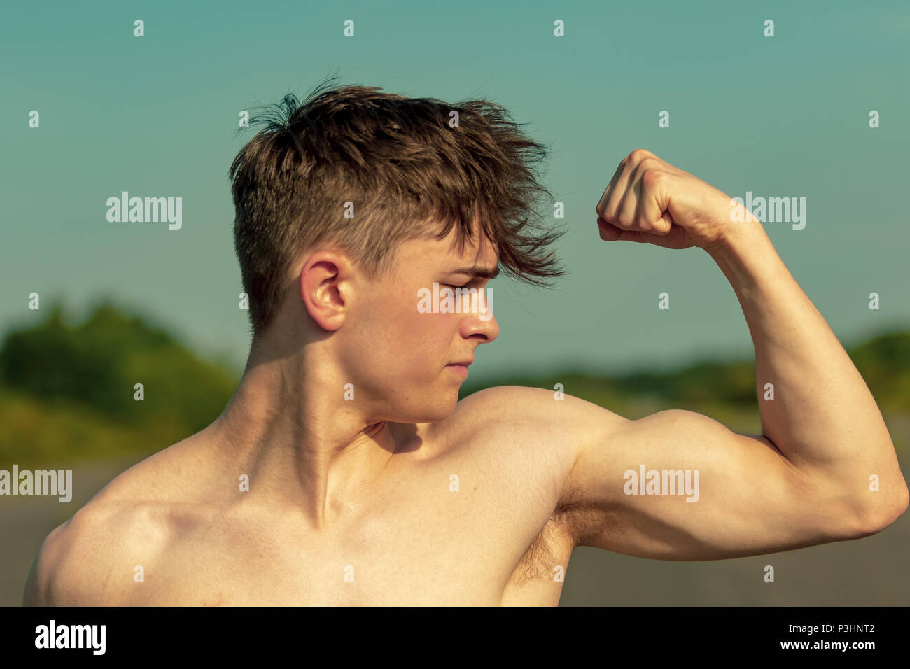 young-adult-male-flexing-his-bicep-muscles-shirtless-on-a-warm-summer-s