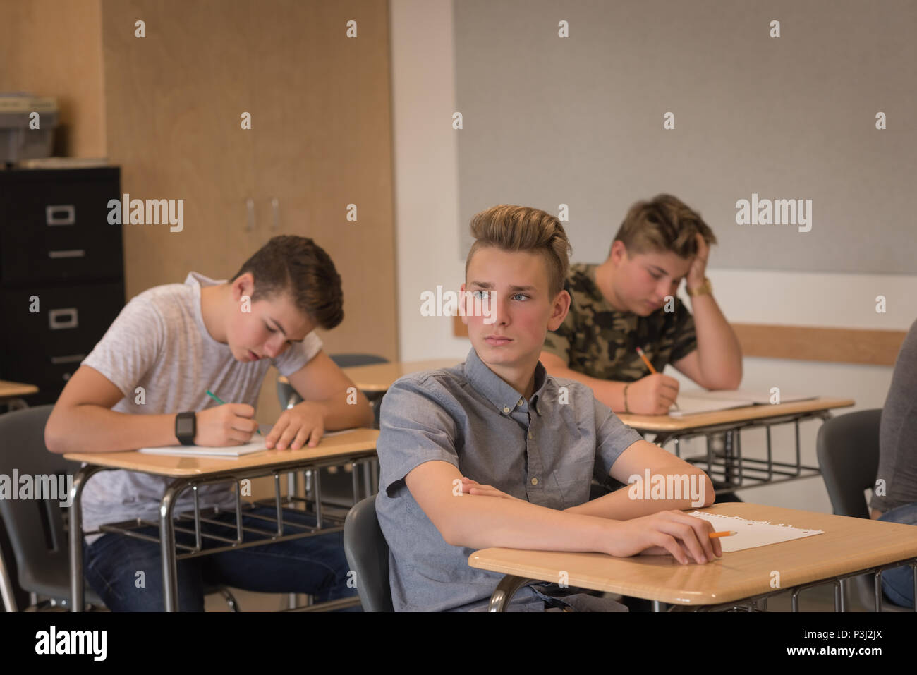 Thoughtful teenage boy sitting in classroom Stock Photo