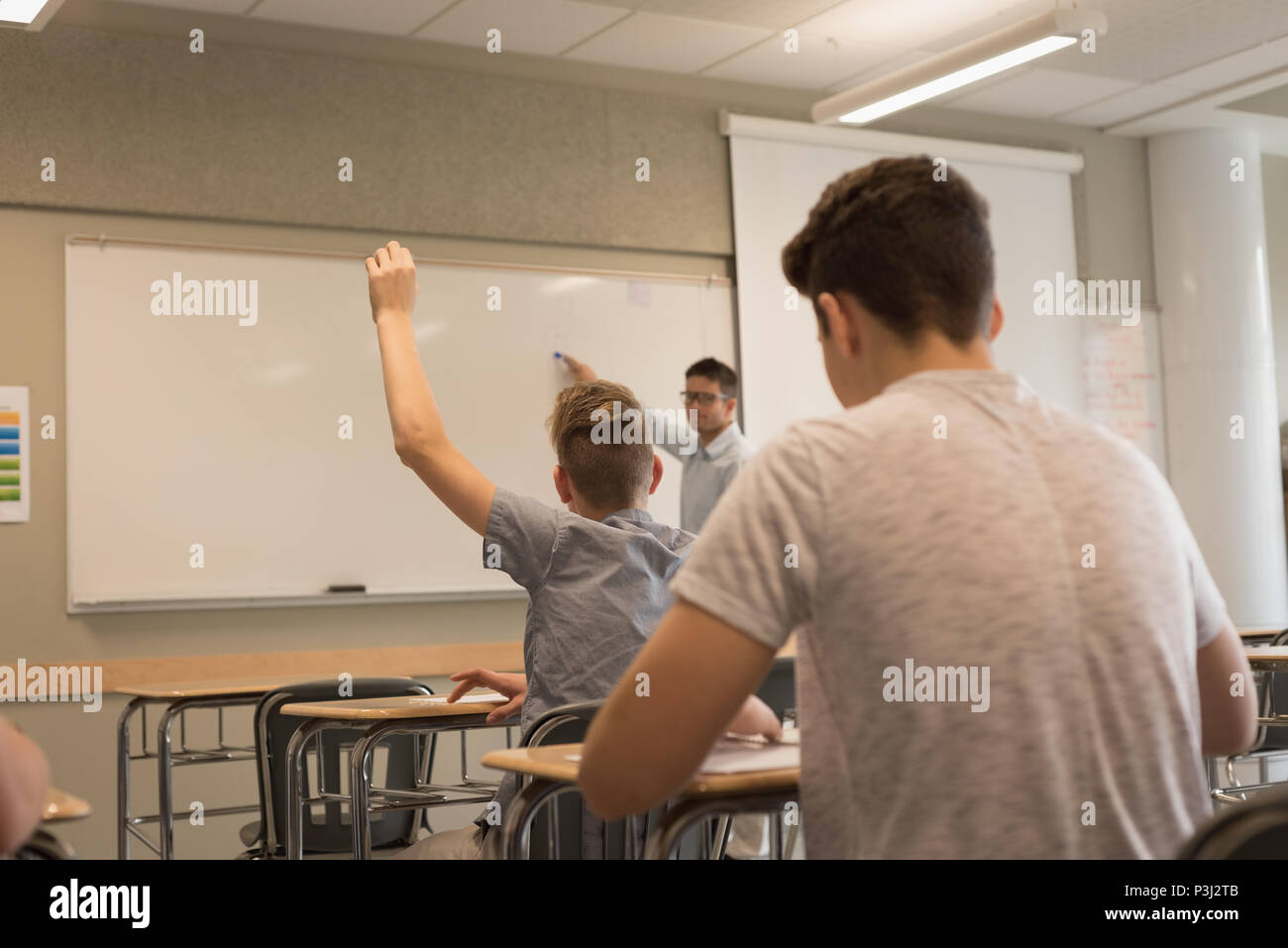 University student raising hand in classroom Stock Photo