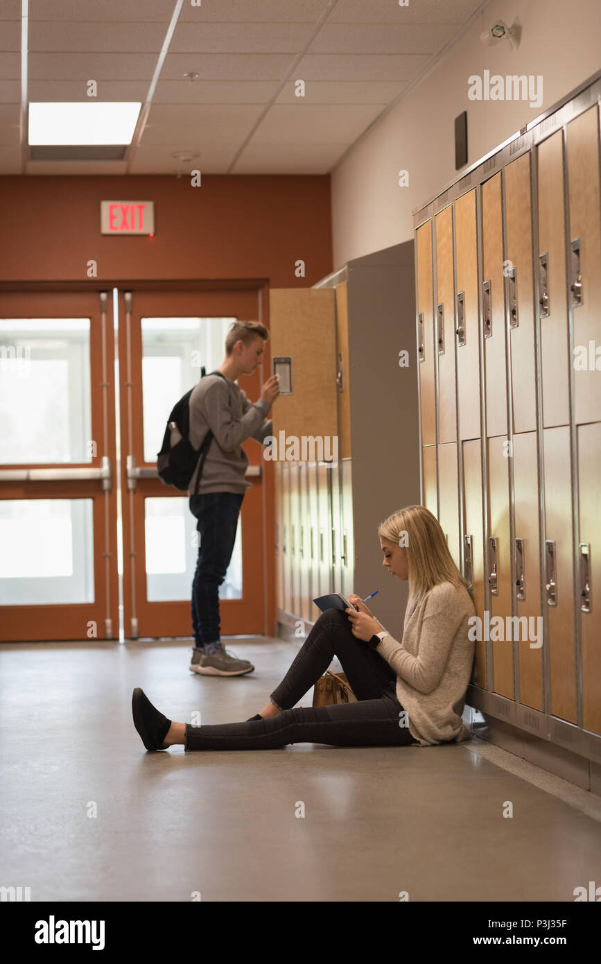 Teenage girl studying in locker room Stock Photo