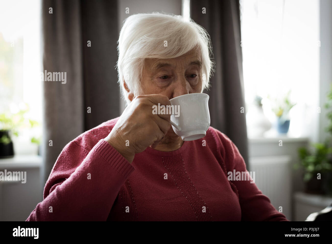 Senior woman having cup of tea in living room Stock Photo