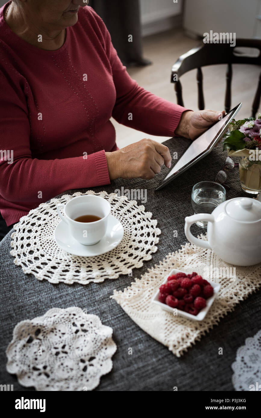 Senior woman using tablet in living room Stock Photo