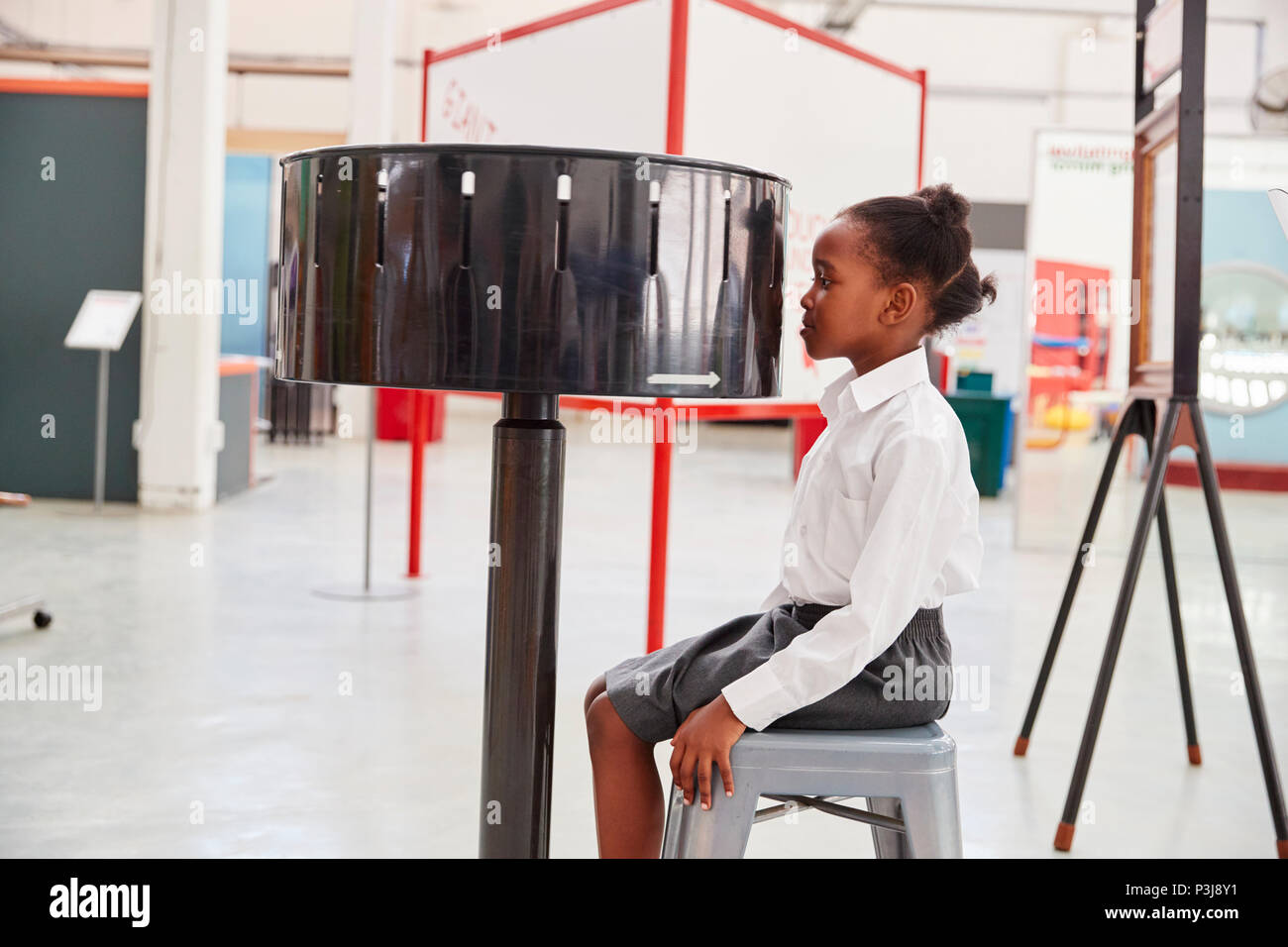 Schoolgirl sitting in front of zoetrope at a science centre Stock Photo