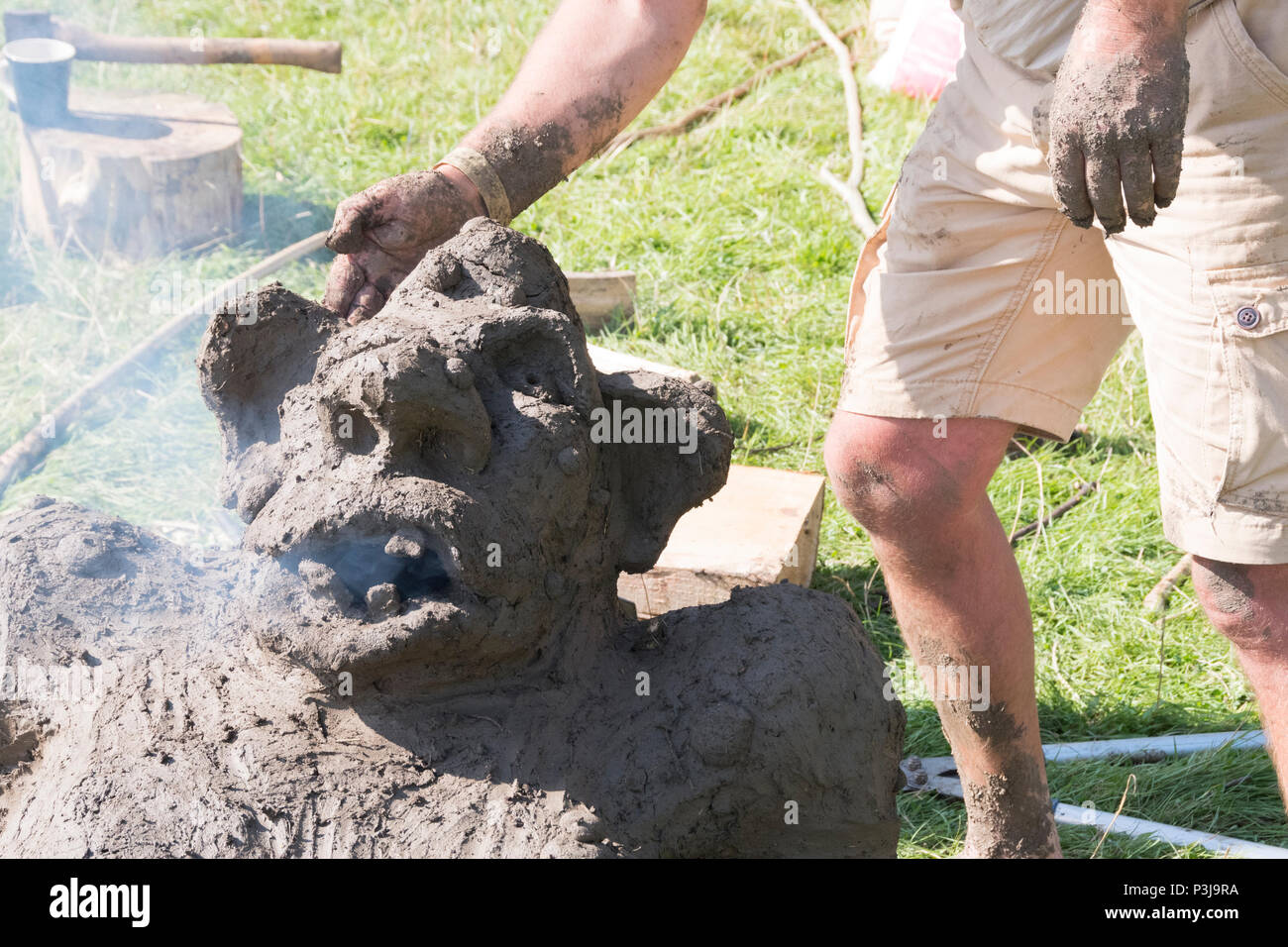 Chepstow, Wales – Aug 14: smoke comes from the mouth of a troll earth oven drying through first bake on 14 Aug 2016 at The Green Gathering Festival Stock Photo