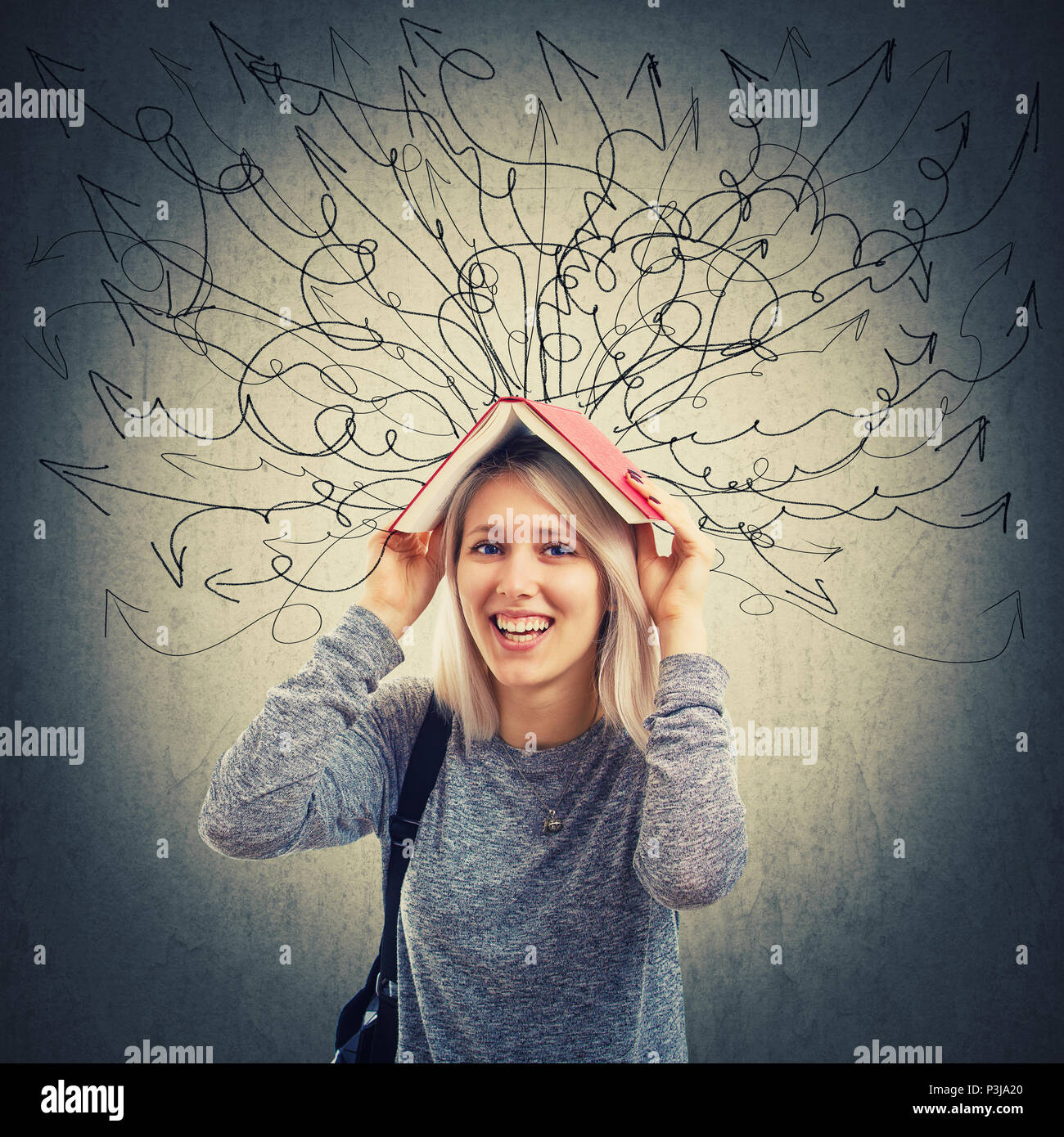 Pretty smiling young woman holding a opened book over her head to prevent escaping thoughts and accumulated knowledge as hundreds of arrows and curves Stock Photo