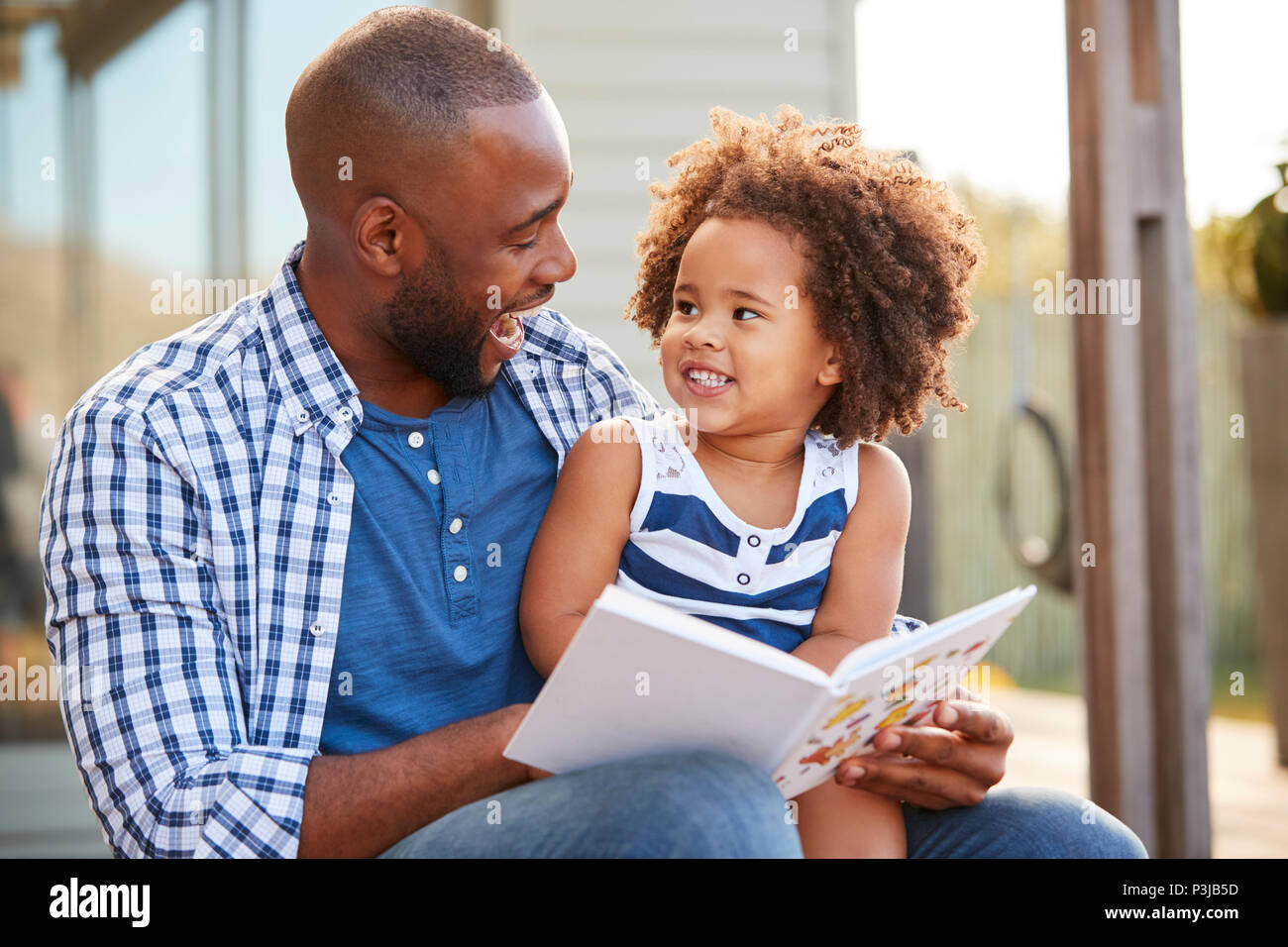 Young black father and daughter reading book outside Stock Photo