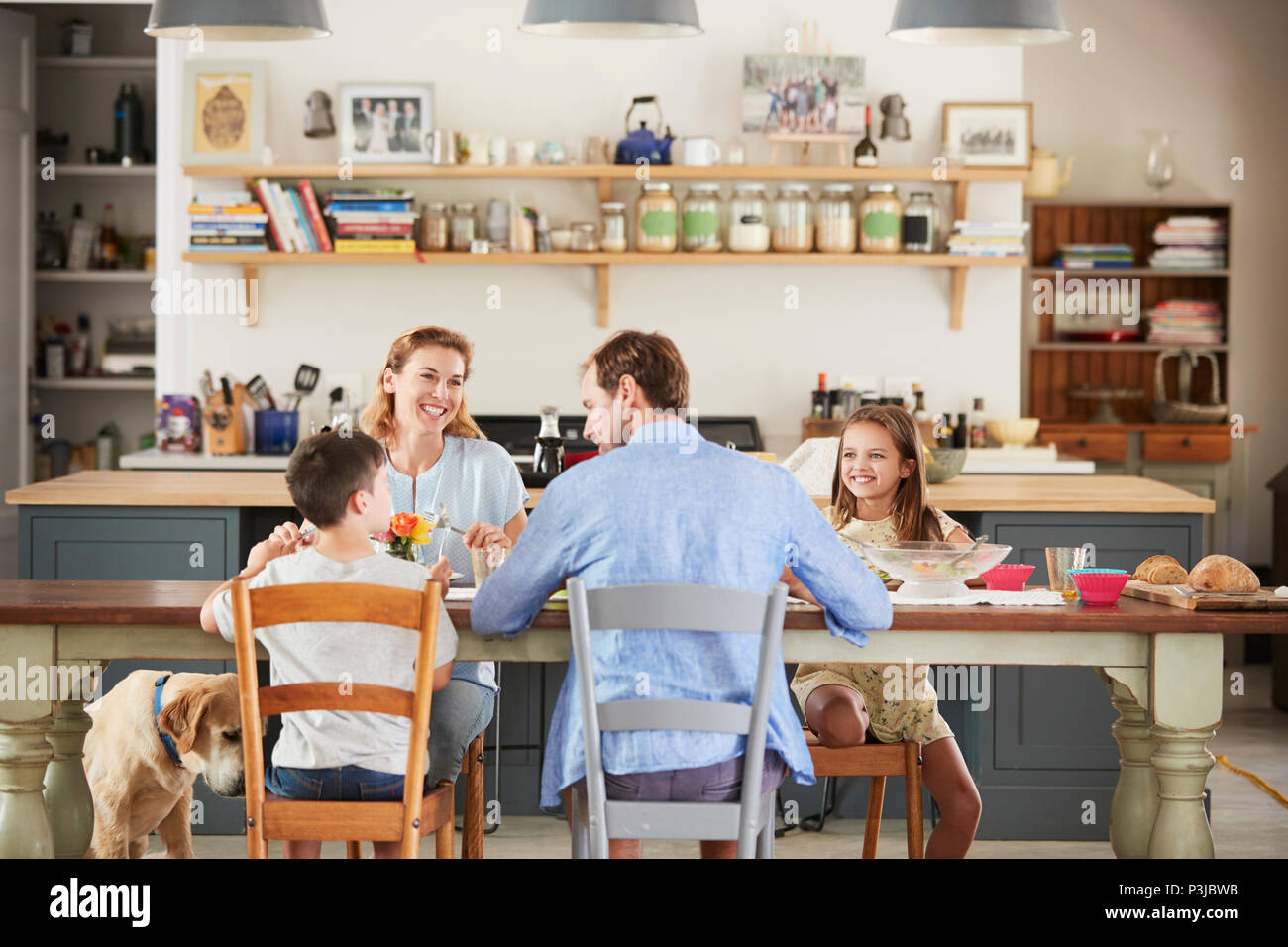 Family with dog eating together at the table in kitchen Stock Photo