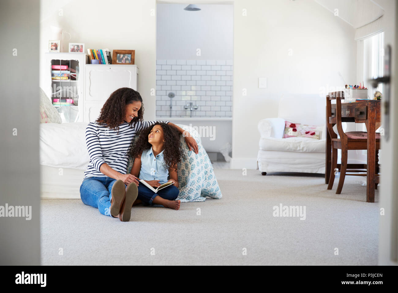 Mother and daughter reading a book in girl's room Stock Photo