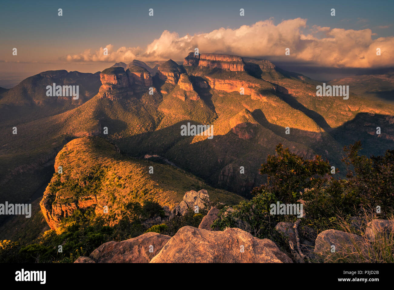 A wide shot of the Three Rondavels and surrounding landscape lit up with dramatic texture and form at sunset golden hour. Mpumalanga, South Africa Stock Photo