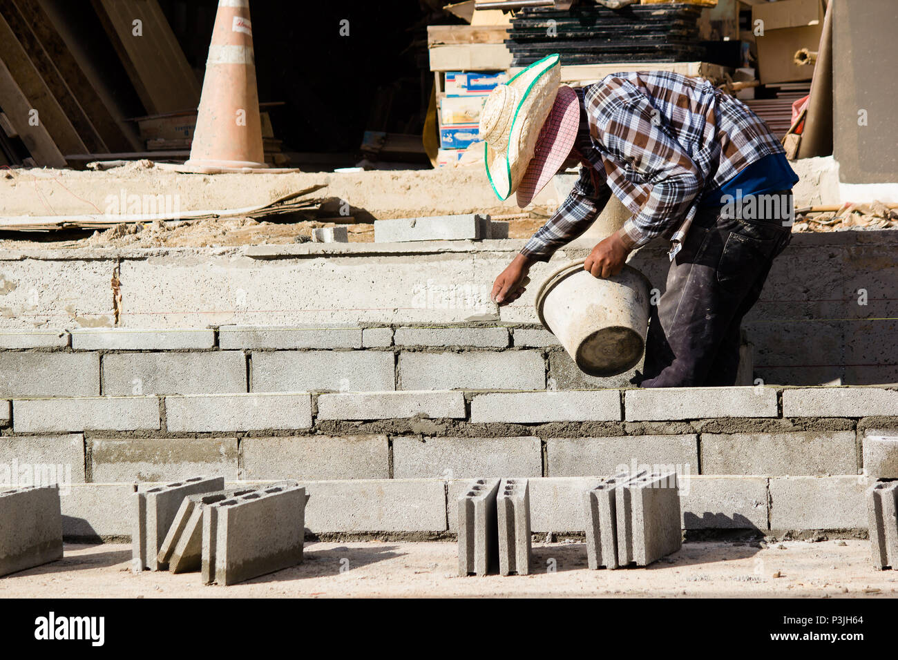 Mason or Brick builders are building cement brick wall in construction site.  Workers are building buildings or buildings for housing. Stock Photo