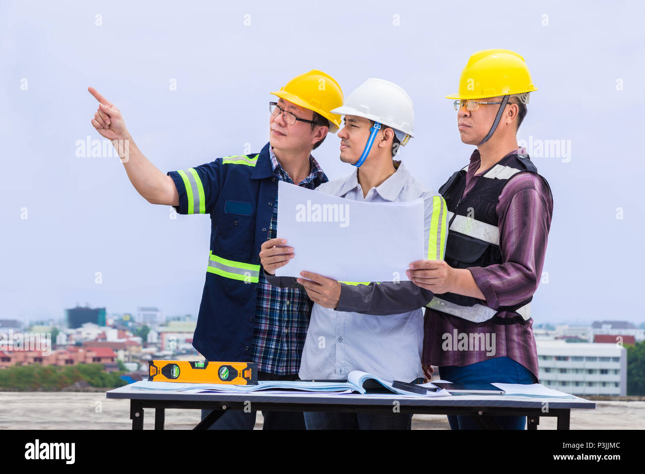 Asian construction engineer and his foremen working together and checking progress at construction site, good for teamwork and engineering theme Stock Photo