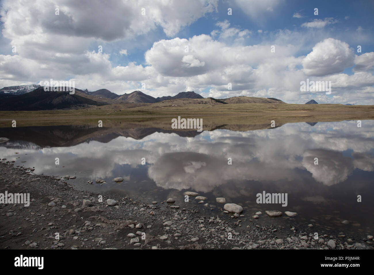 Bean Lake reflects the Rocky Mountain Front across its waters, as well as a bevy of clouds. Stock Photo