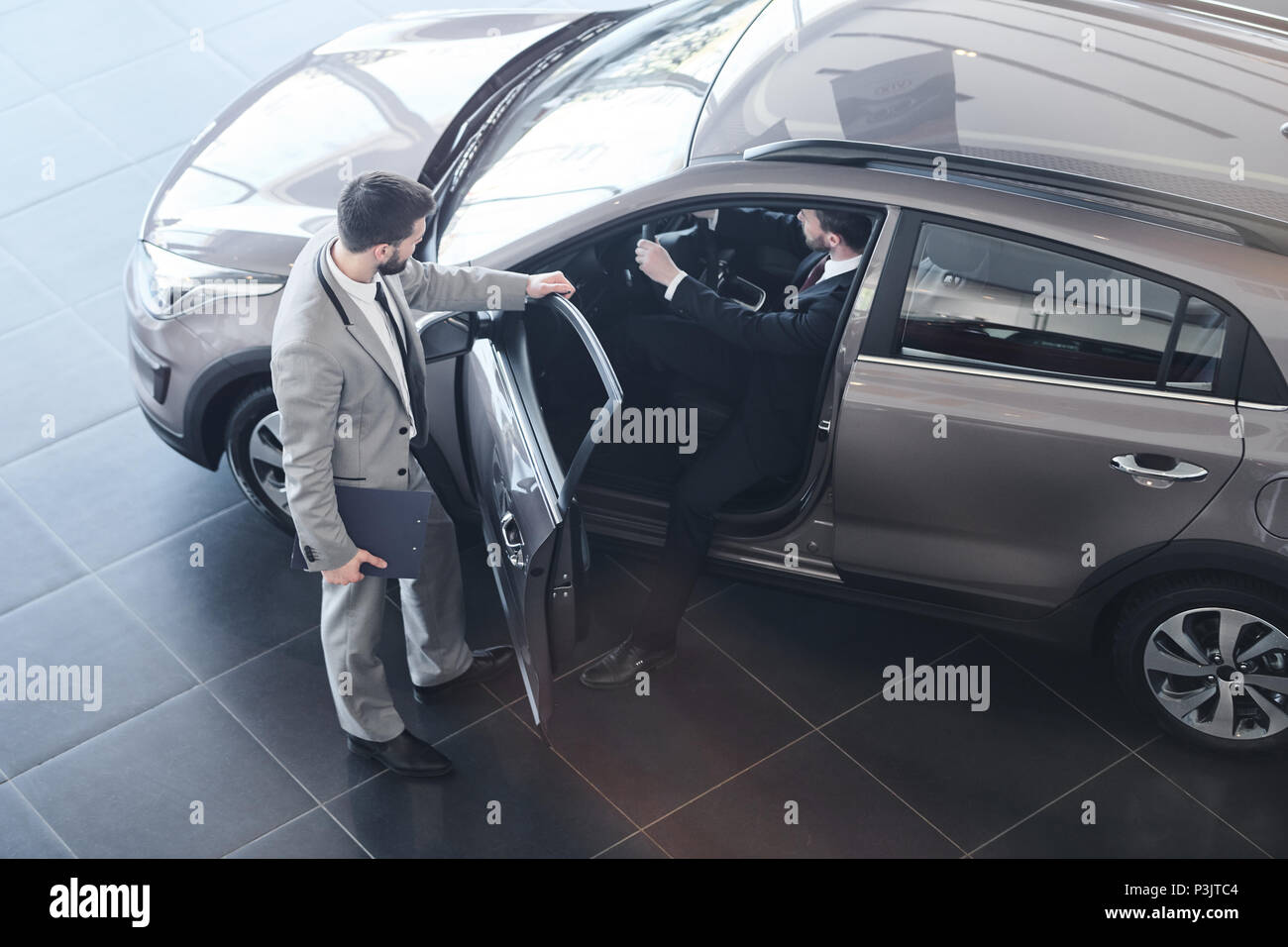 Car Salesman Opening Door to Client Stock Photo