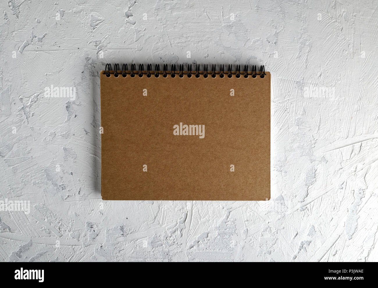 notebook on a black iron spring with brown empty sheets on a white background, close up Stock Photo