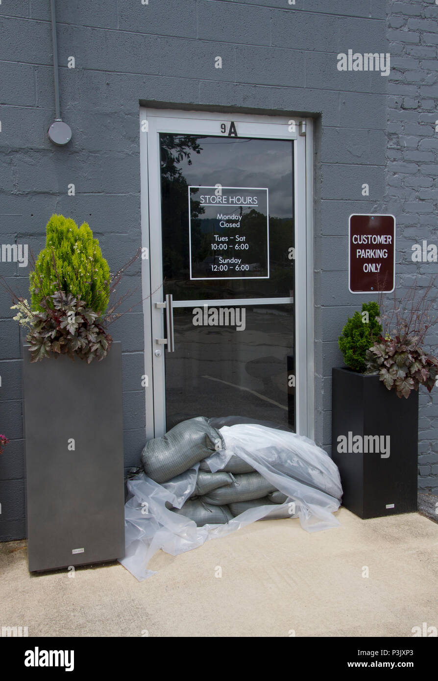 BILTMORE FOREST, NORTH CAROLINA-MAY 30, 2018: A glass store door has sand bags piled on the ground in front of it to protect from rising flood waters  Stock Photo