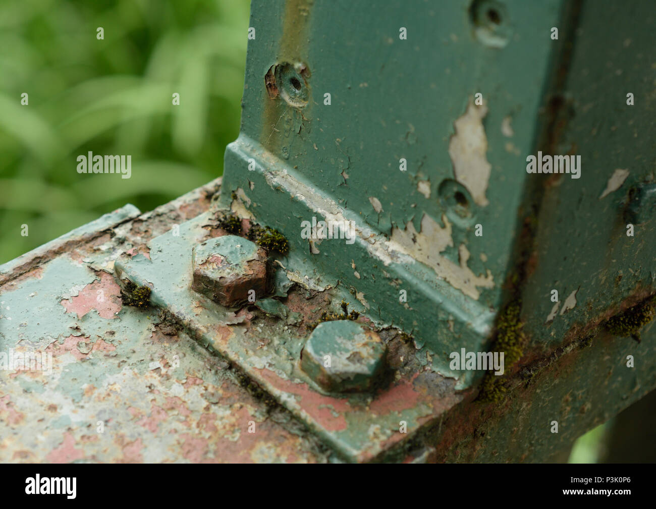 Steel bracket with rusty bolt head, green paint peeling off steel bracket in burrs country park bury lancashire uk Stock Photo