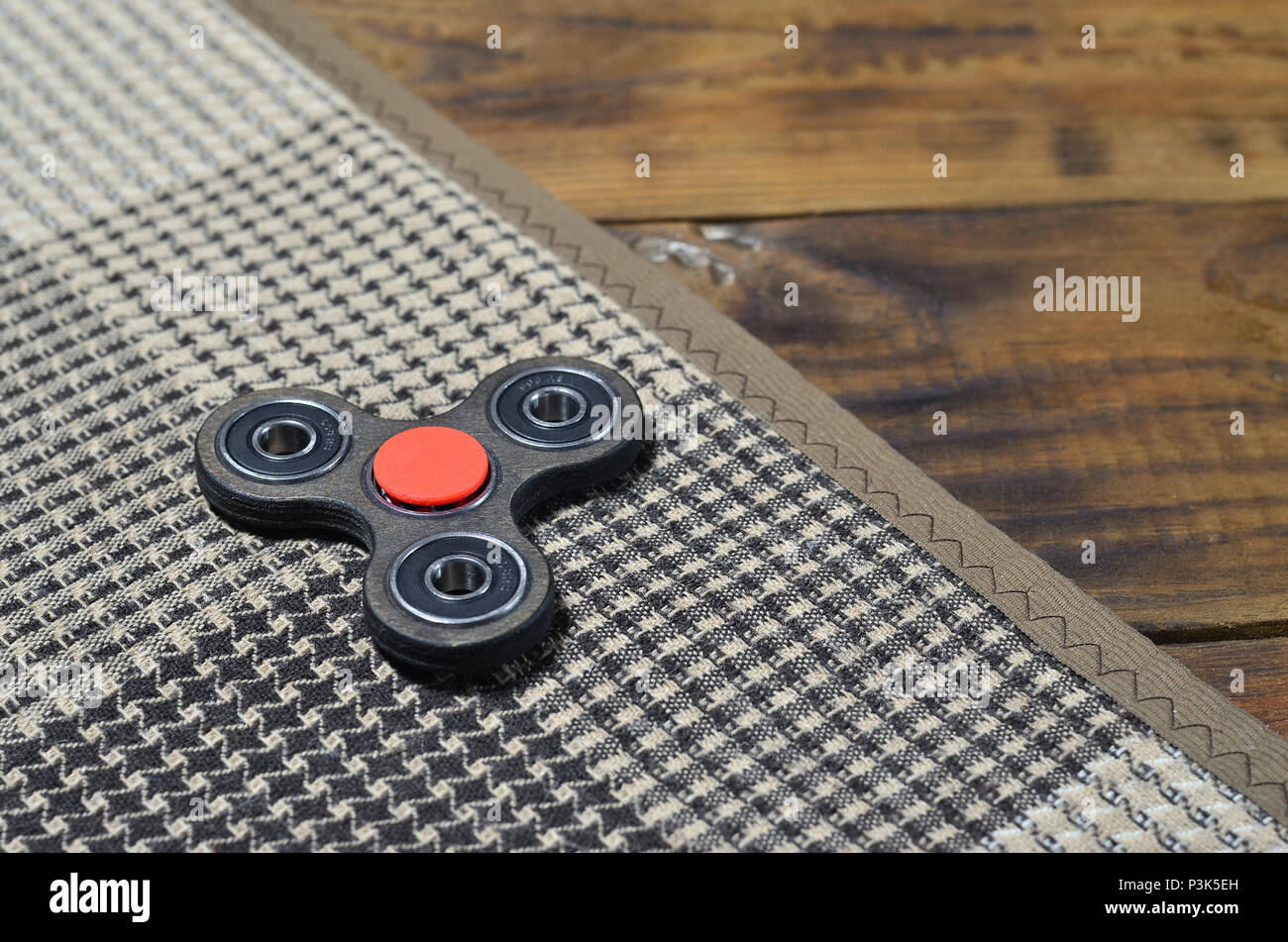 A rare wooden handmade spinner lies on a checkered plaid on a brown wooden  background surface. Trendy stress relieving toy Stock Photo - Alamy