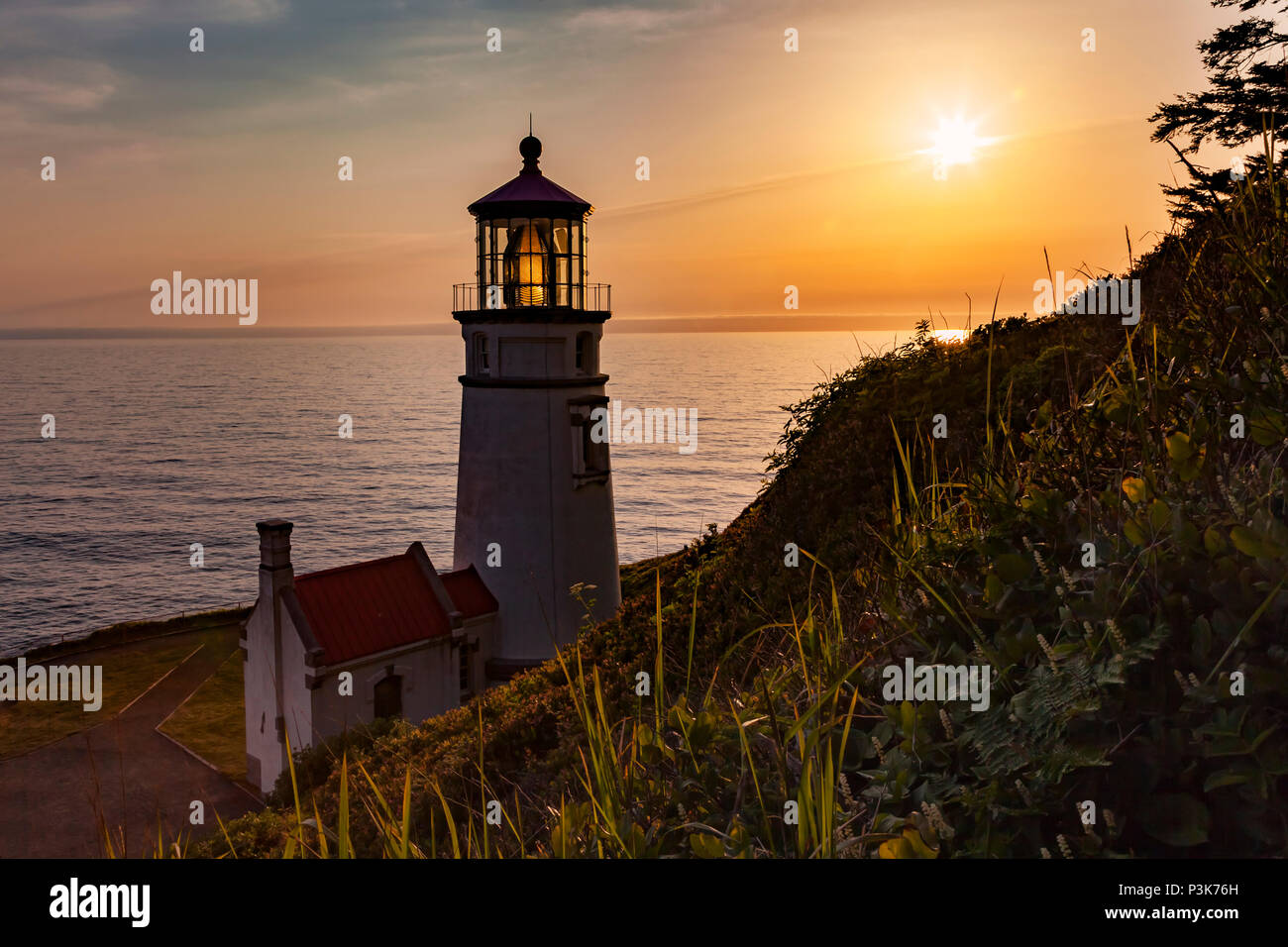 The sun sets to the west of the Haceta Head Lighthouse along Oregon's Central Coast north of Florence. Stock Photo