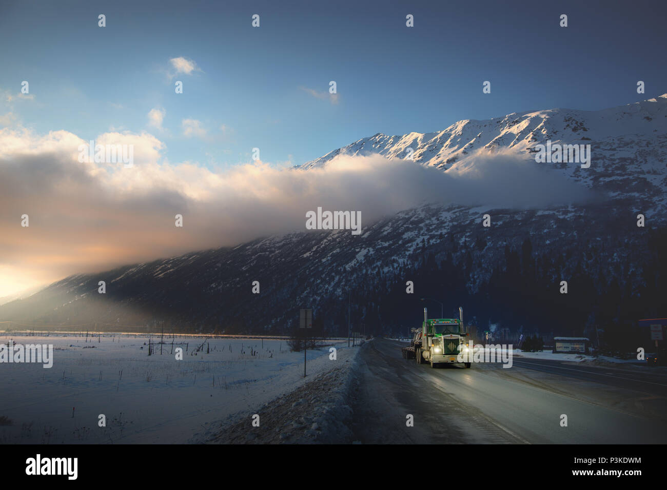 Truck driver driving in Alaska during sunset winter snowy conditions Stock Photo