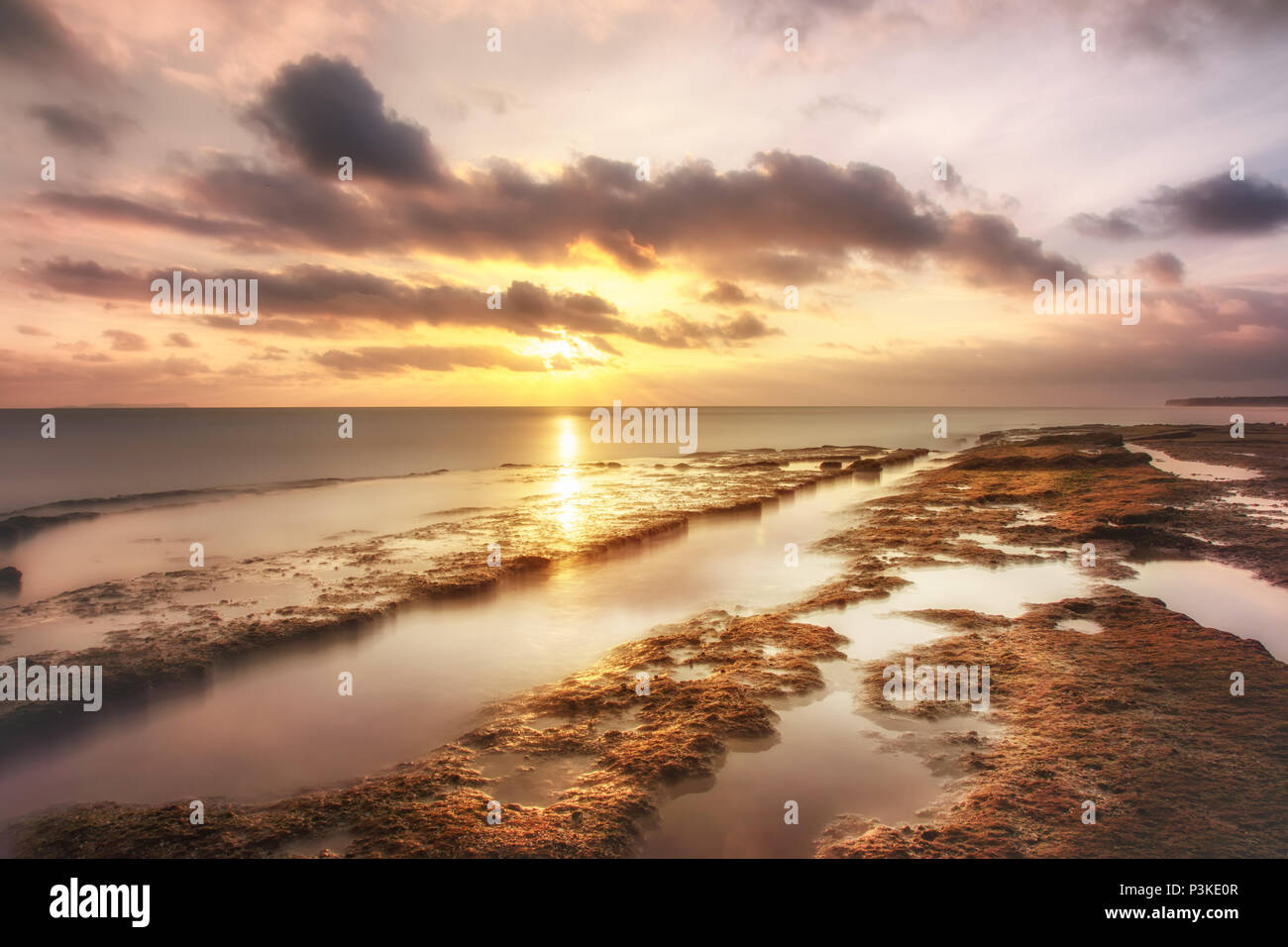 Sunset in Ecuador by the sea ocean shore beach rocks clouds long exposure Stock Photo