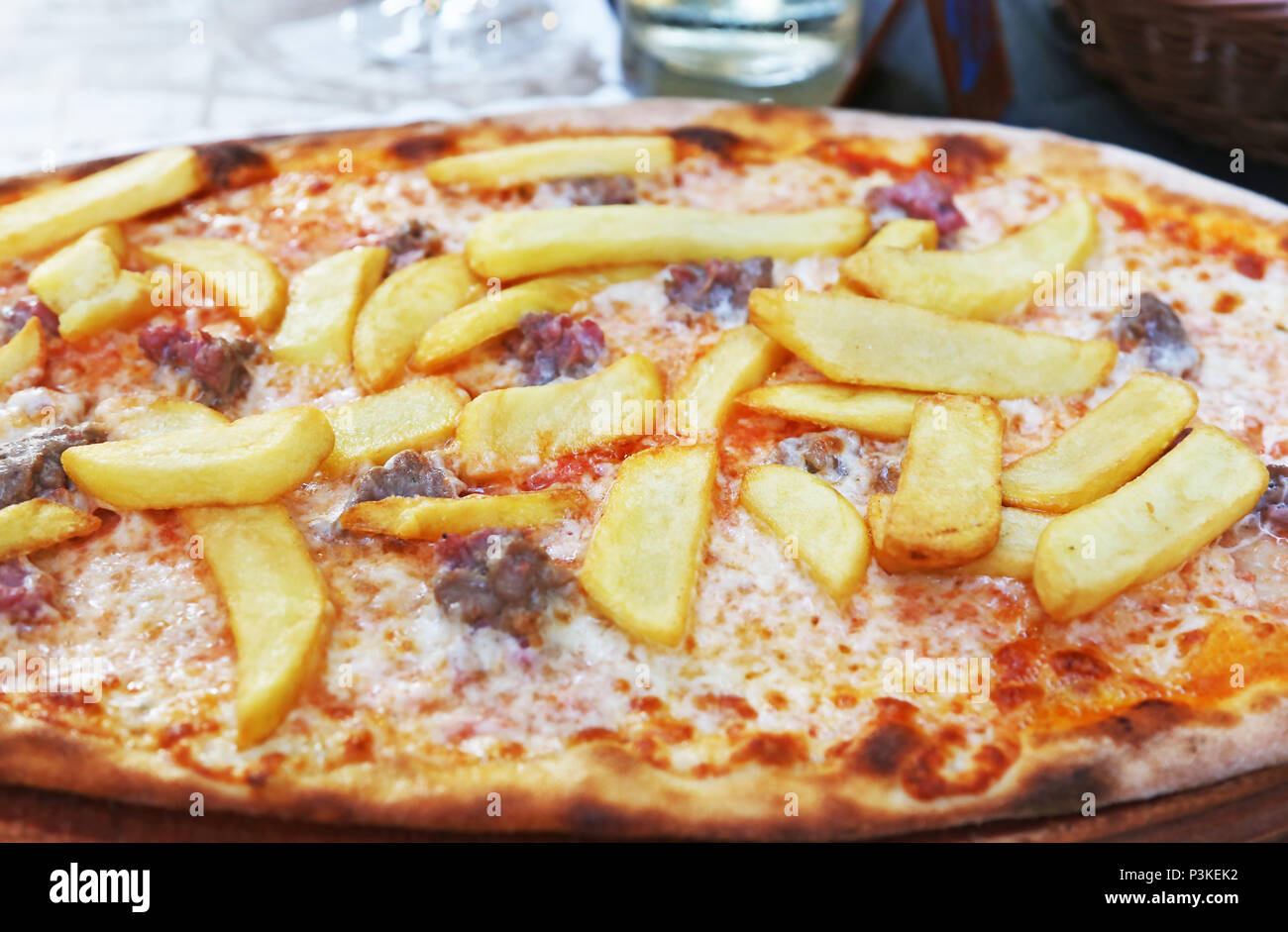 traditional italian pizza with potato fries, sausages, cheese and