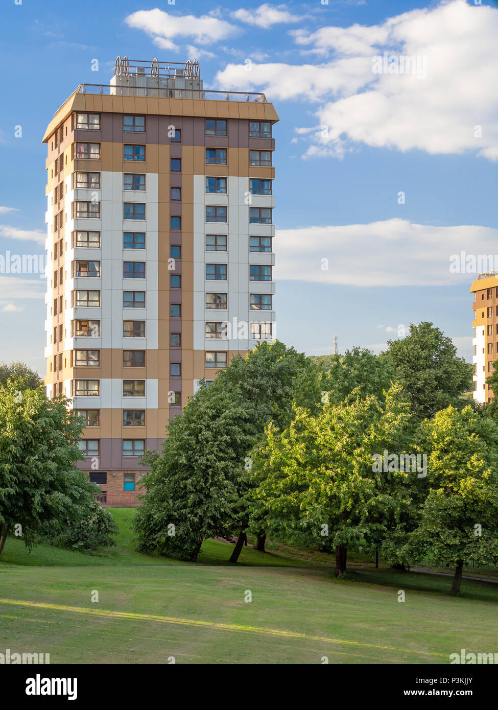 Apartment complex next to a park set against a blue sky Stock Photo