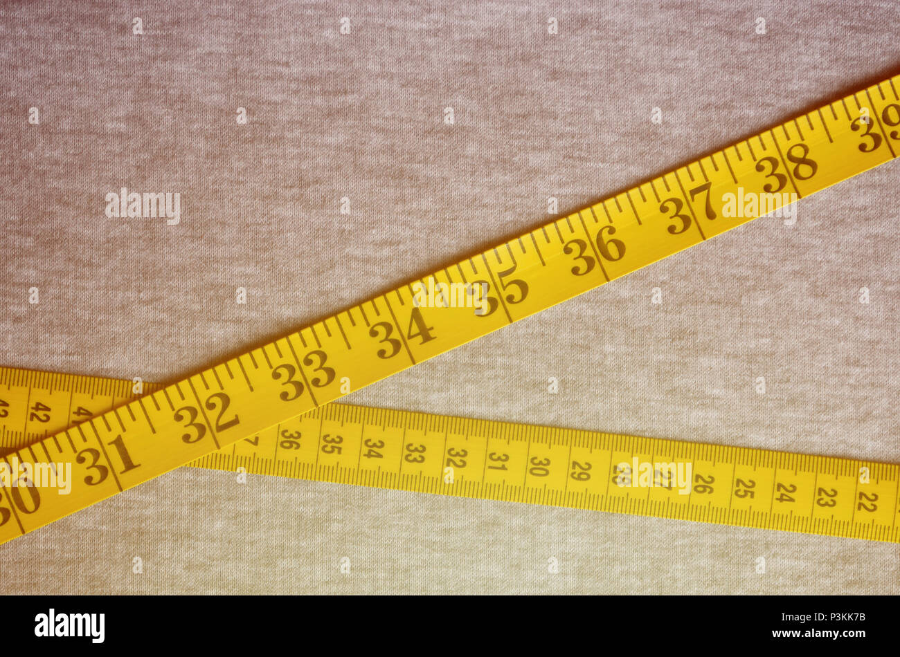 Yellow measuring tape with numerical indicators in the form of centimeters  or inches lies on a gray knitted fabric. Concept industry associated with s  Stock Photo - Alamy