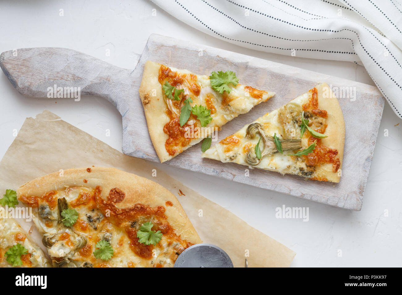 Two pieces of cheese pizza with artichoke and arugula Stock Photo