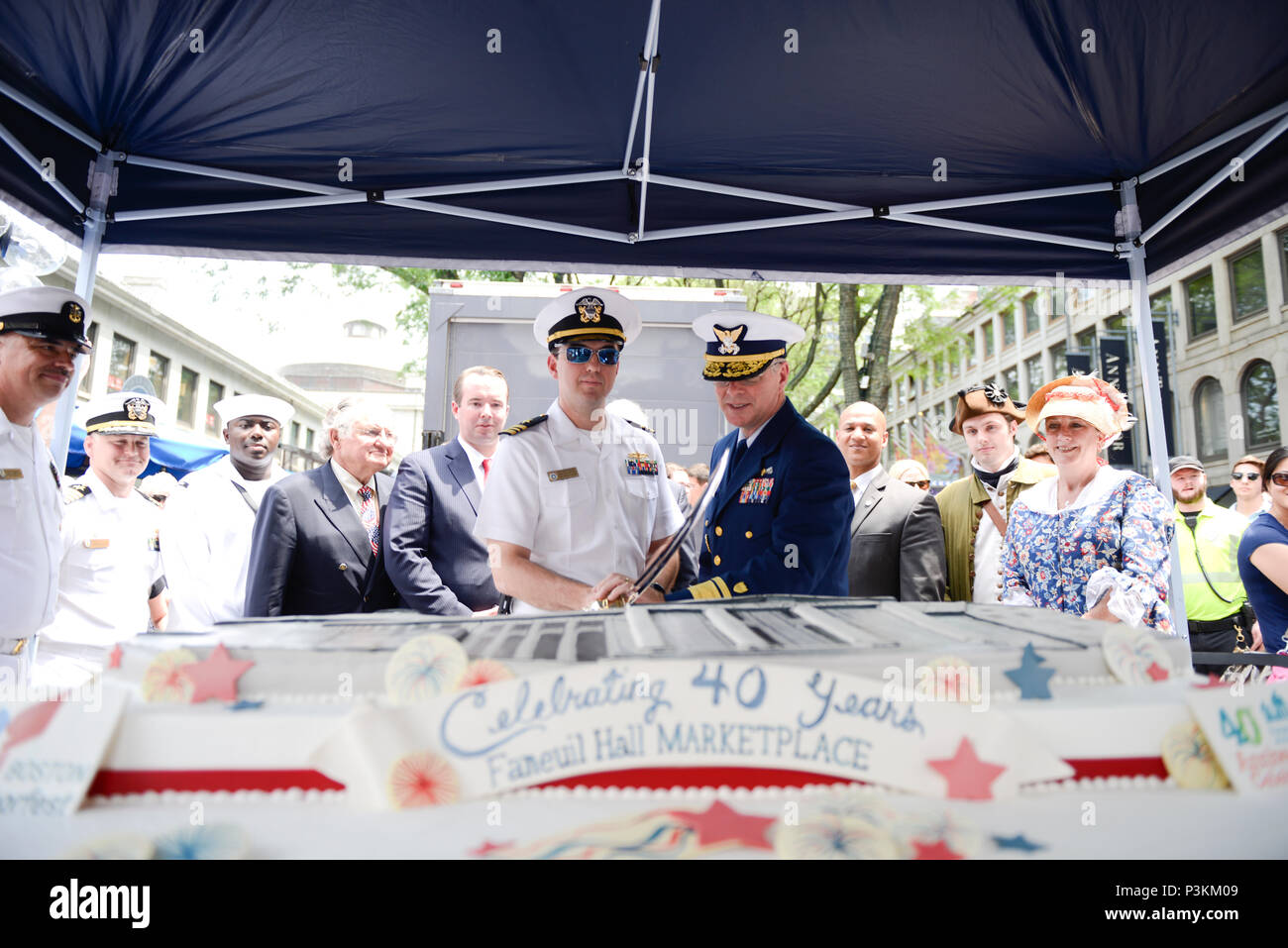 Coast Guard Rear Adm. Steven Poulin, commander First Coast Guard District  (Center right,) cuts a cake with Navy Lt. Cmdr. Tim Anderson, executive  officer of the U.S.S. Constitution, at the 2016 Boston