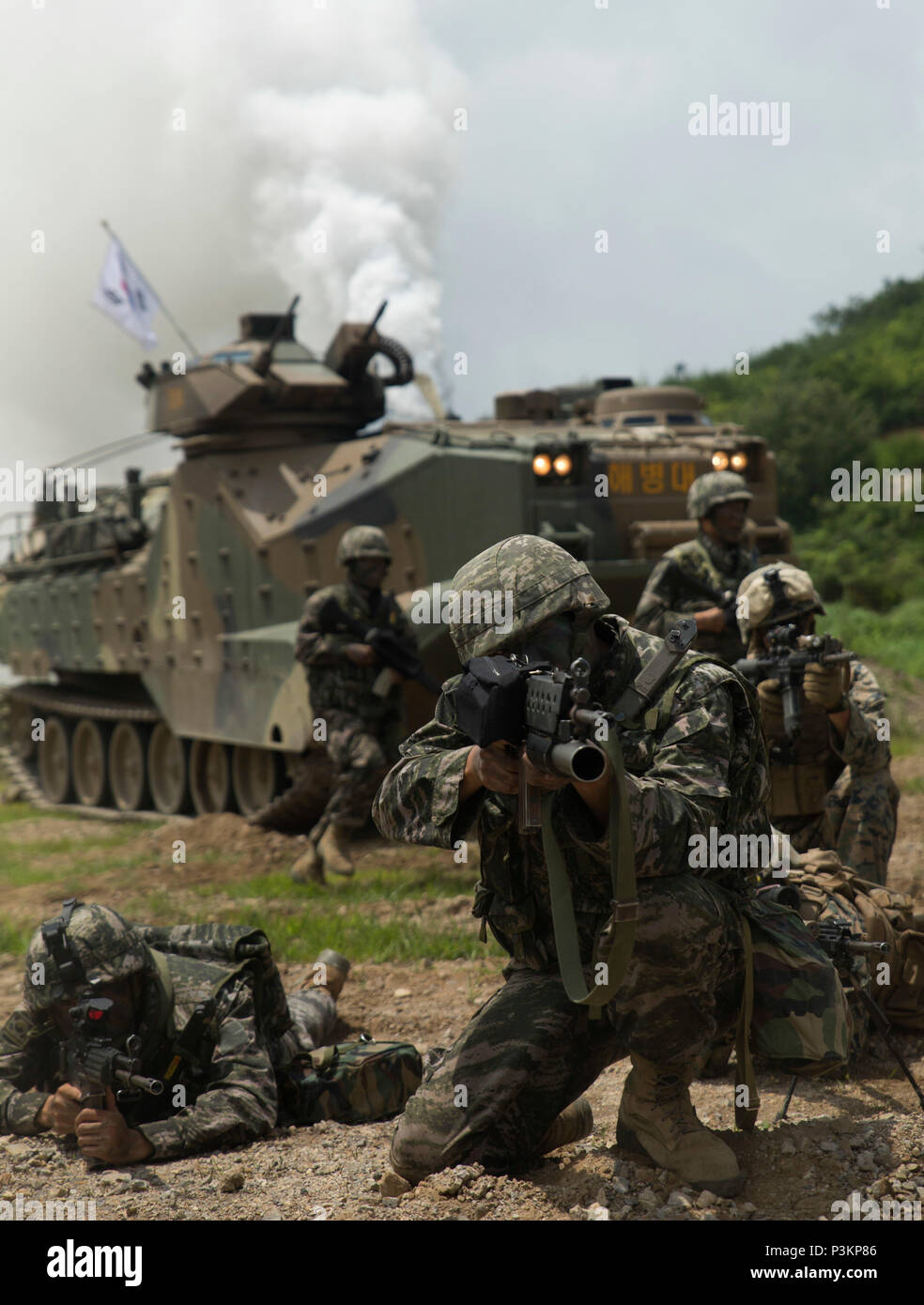 A Republic of Korea Marine sights in alongside U.S. Marines as ROK Assault Amphibious Vehicles shoot off smoke behind them July 6, 2016 at Suseong Range, South Korea, during a Korean Marine Exchange Program. The goal of the KMEP is to sustain the combined force and enhance the ROK-U.S. team at the tactical level to build combined war fighting capabilities. During this exercise, the Marines carried out a bilateral regimental-sized Marine Air Ground Task Force operation for the first time. The ROK Marines were a part of 73rd Battalion, 7th Regiment, 1st Marine Division. The U.S. service members  Stock Photo