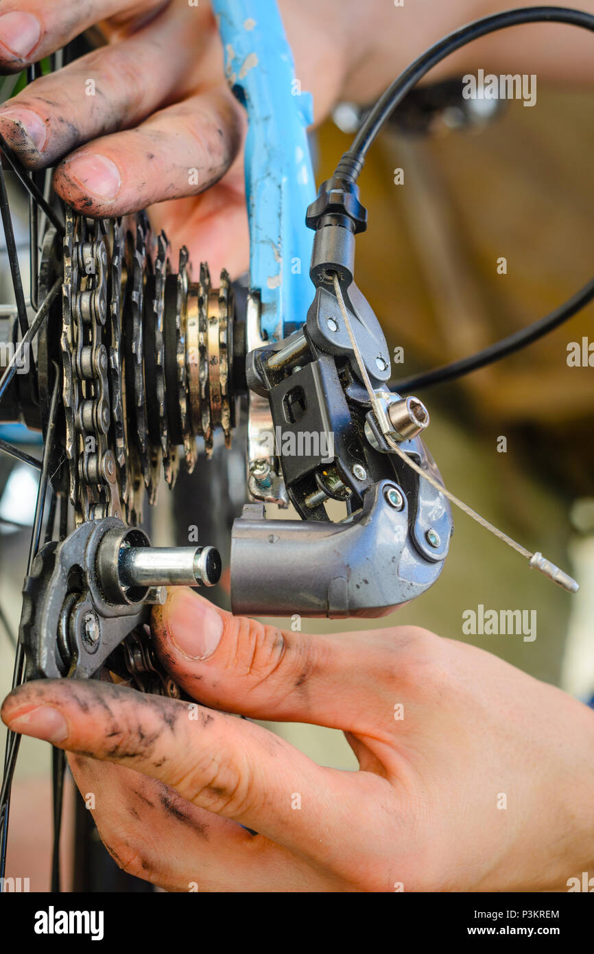 Broken Bicycle Rear Derailleur. Hands Hold the Parts of the Rear