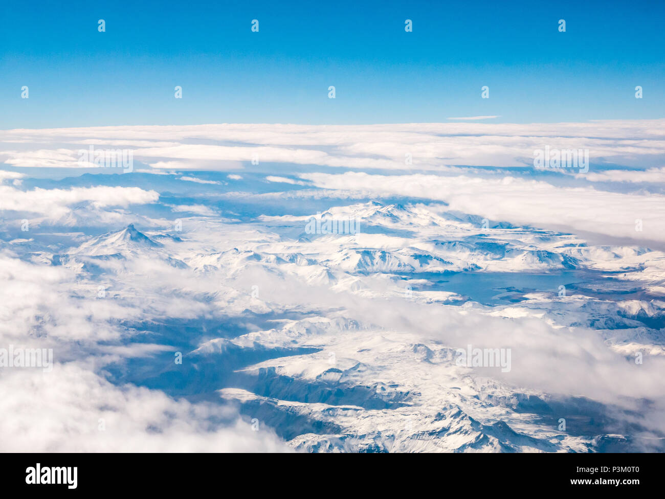 View from aeroplane window of snow covered Andes mountains with cloud cover and lake, Southern Patagonian Ice field, Patagonia, Chile, South America Stock Photo