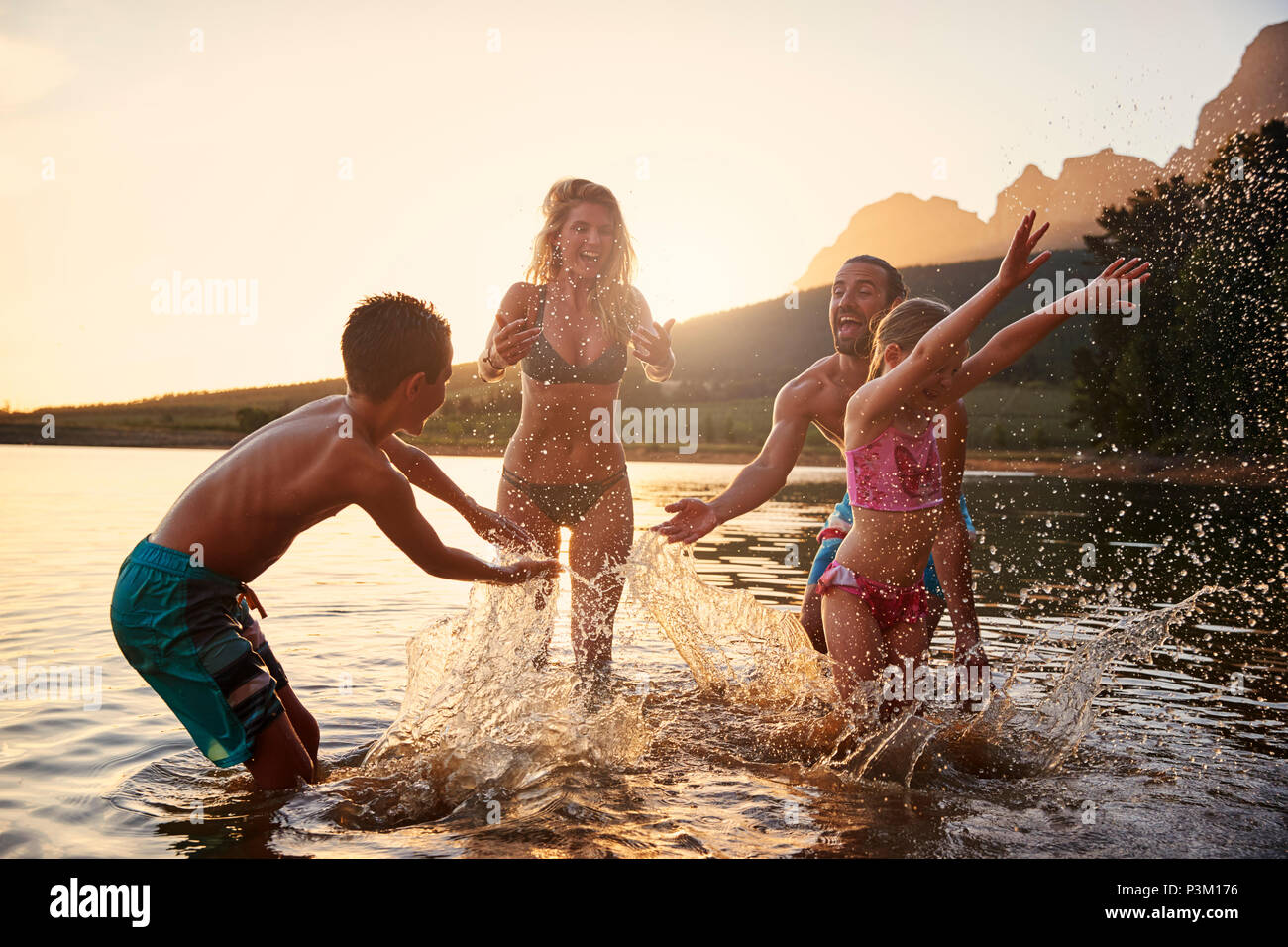 Family Enjoying Evening Swim In Countryside Lake Stock Photo