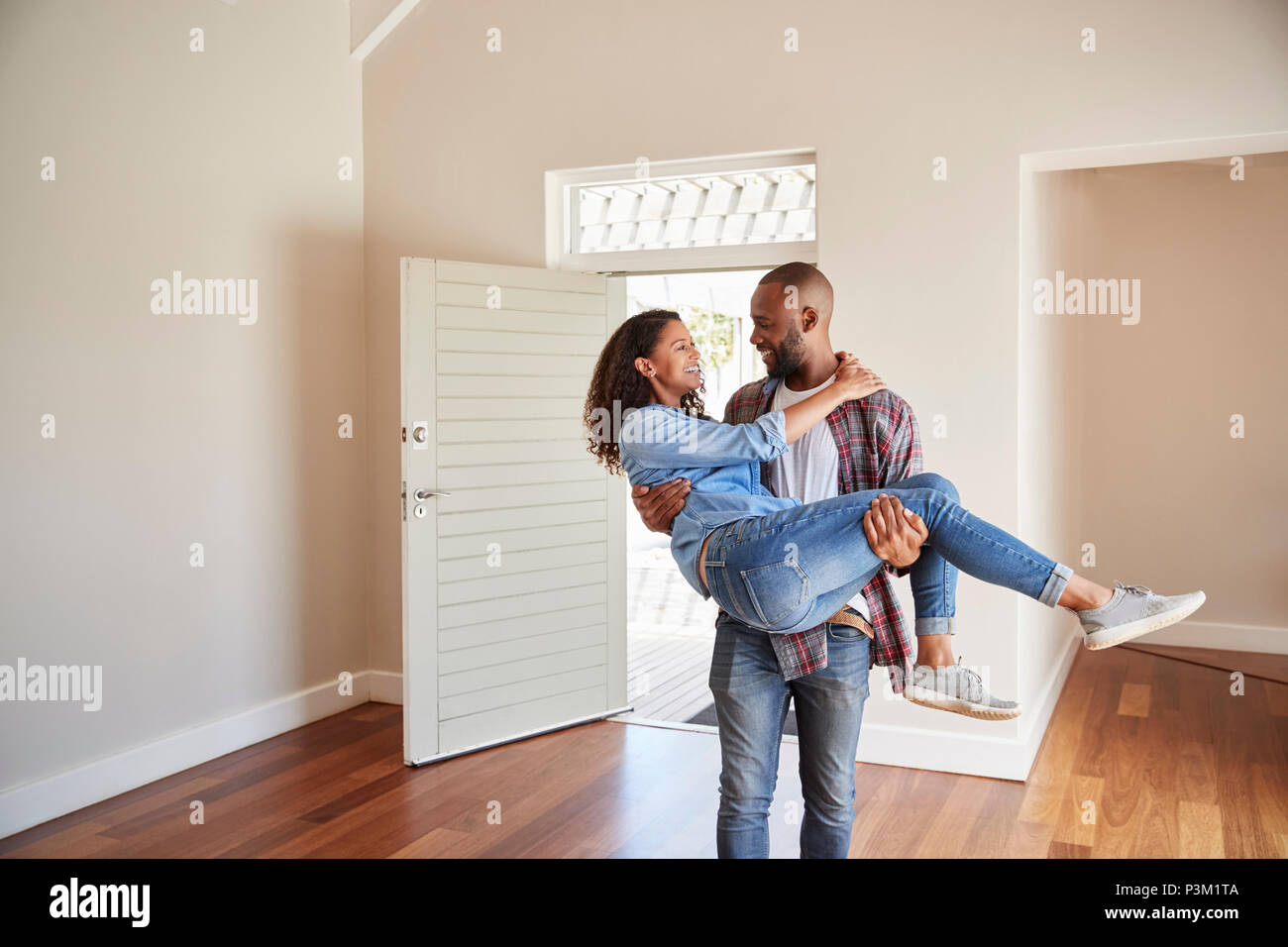Man Carrying Woman Over Threshold Of Doorway In New Home Stock Photo