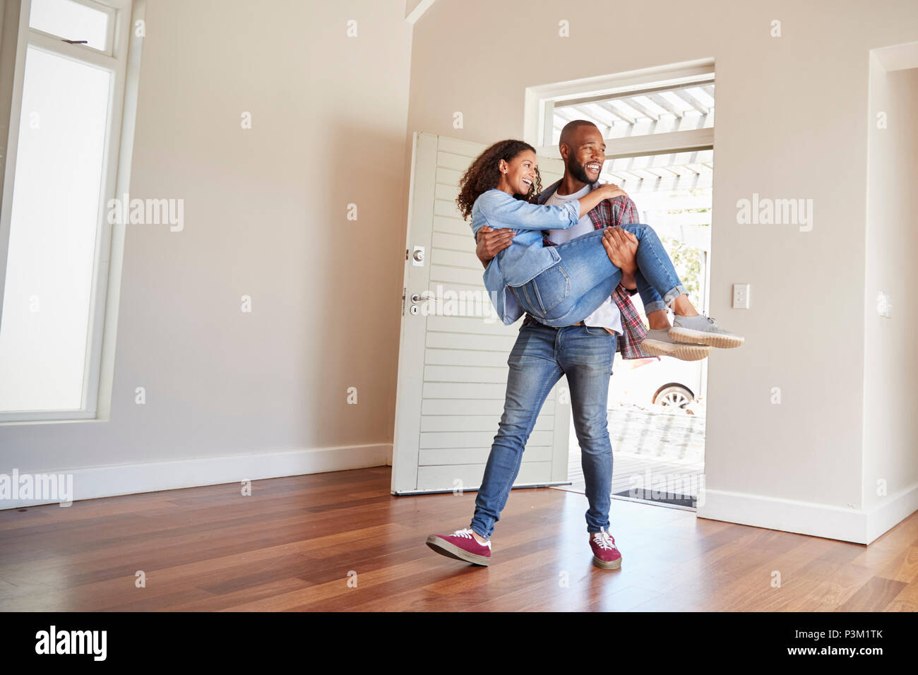 Man Carrying Woman Over Threshold Of Doorway In New Home Stock Photo