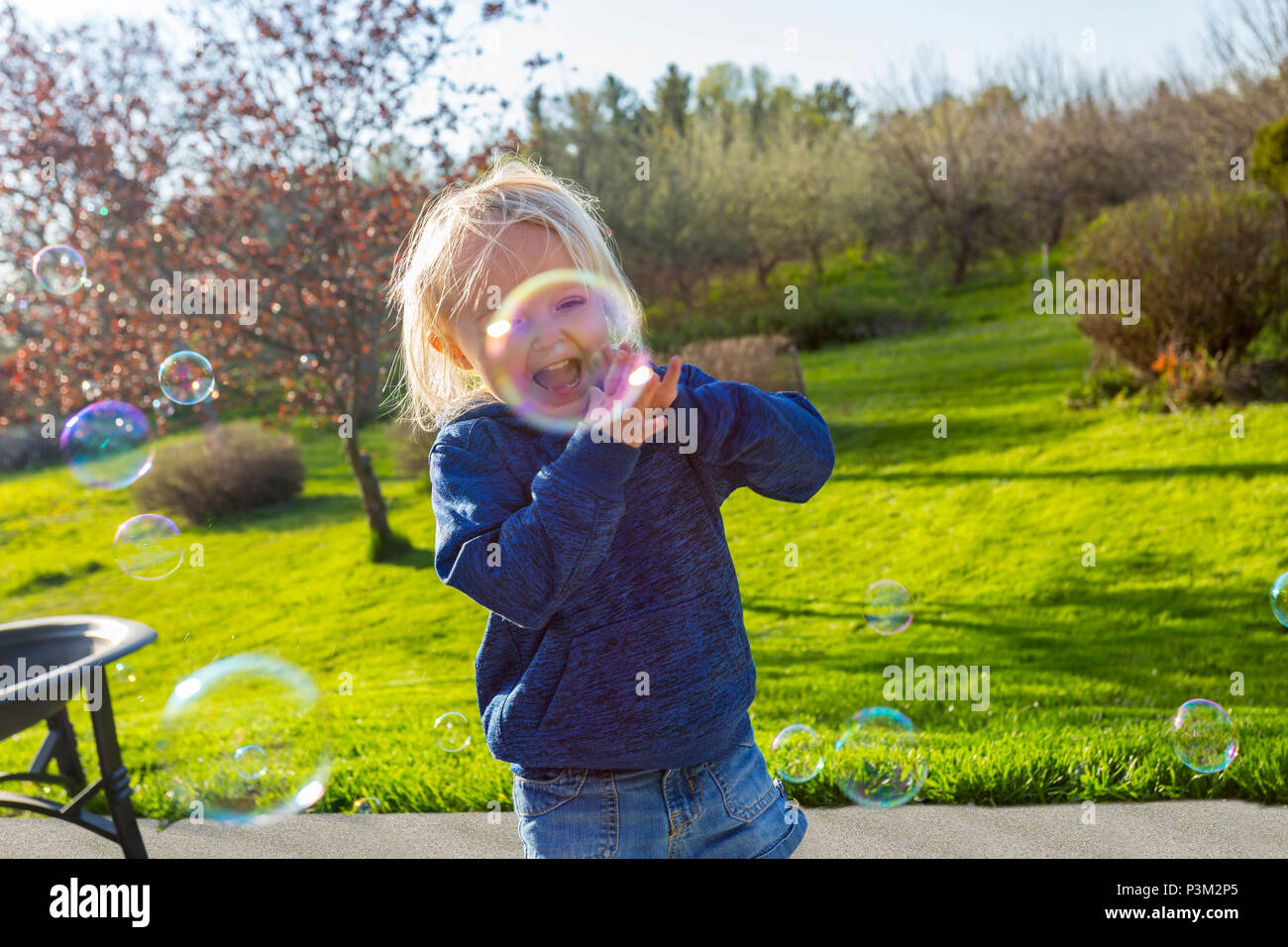 Caucasian toddler playing with soap bubbles outdoors Stock Photo