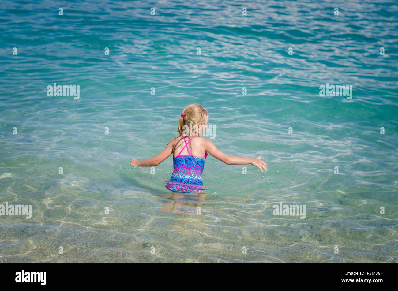 cute little blond girl swimming in the sea back view Stock Photo - Alamy