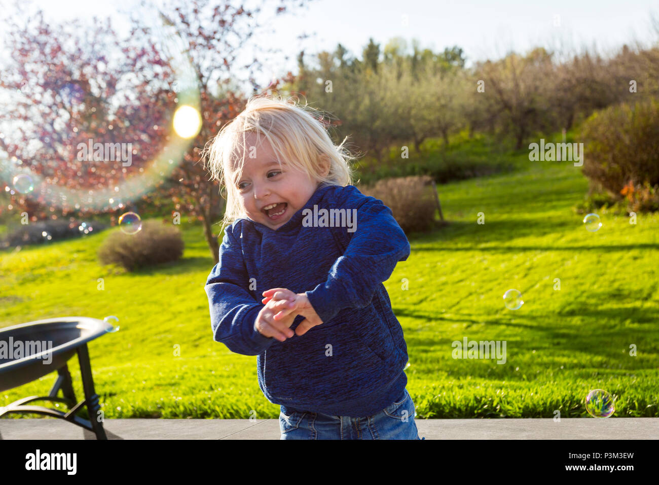 Caucasian toddler playing with soap bubbles outdoors Stock Photo