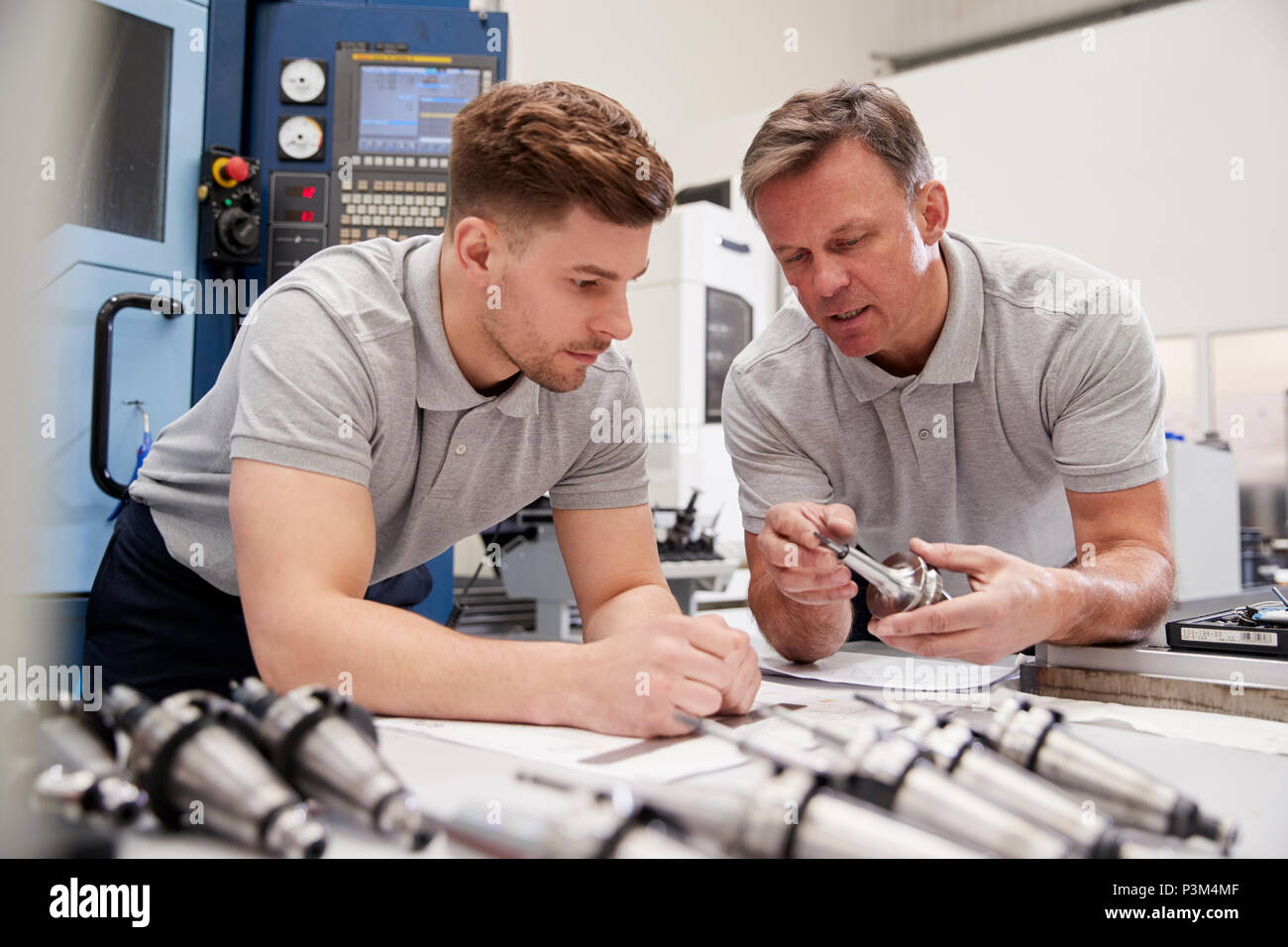 Engineer Showing Apprentice How To Measure CAD Drawings Stock Photo