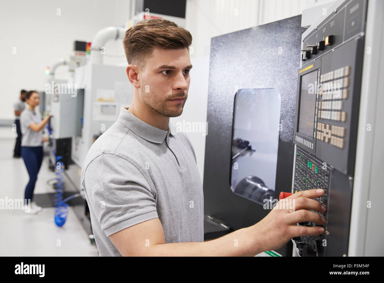 Male Engineer Operating CNC Machinery In Factory Stock Photo