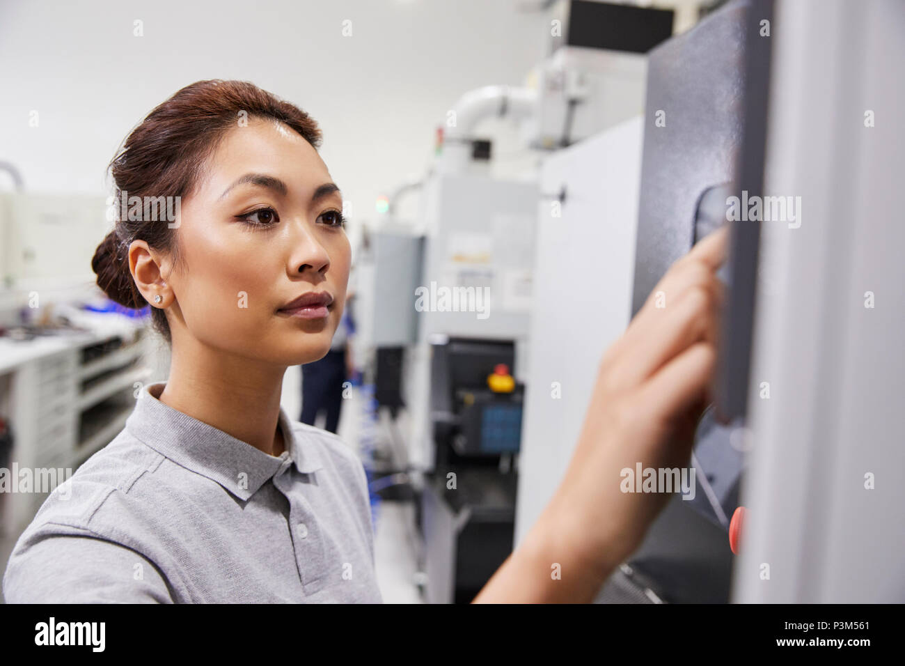 Female Engineer Operating CNC Machinery In Factory Stock Photo