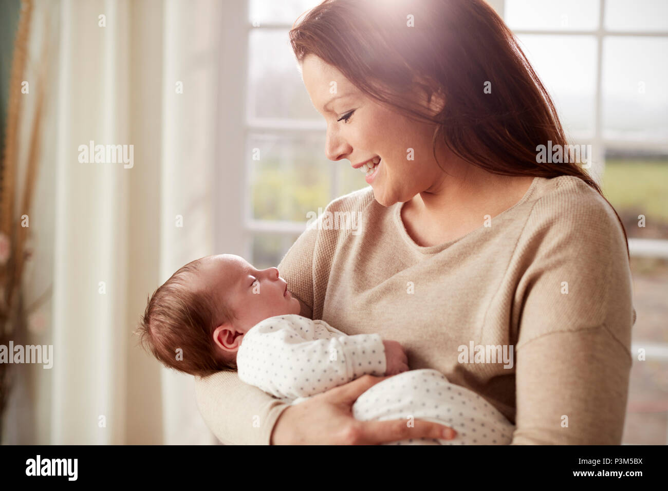 Loving Mother Cuddling Newborn Baby At Home Stock Photo