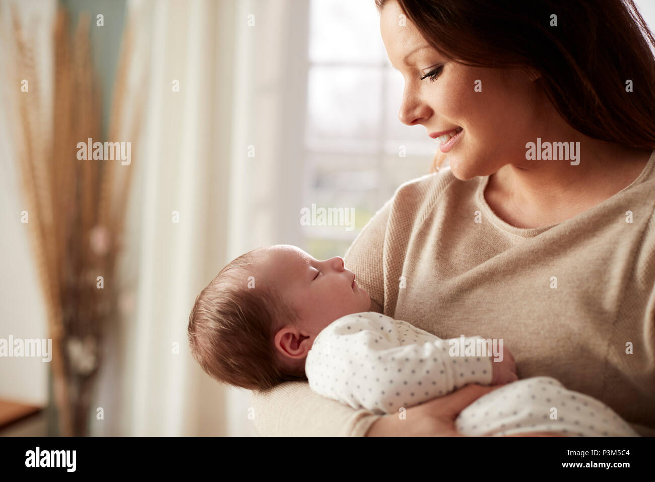 Loving Mother Cuddling Newborn Baby At Home Stock Photo