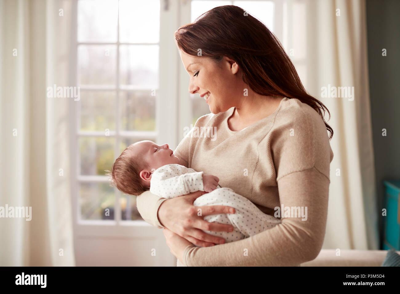 Loving Mother Cuddling Newborn Baby At Home Stock Photo