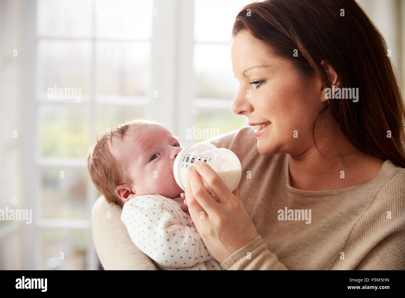 Mother Feeding Newborn Baby From Bottle At Home Stock Photo