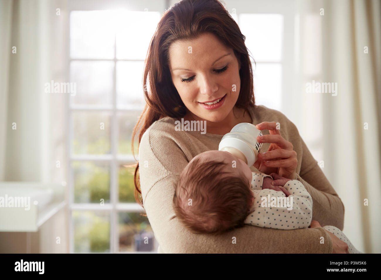 Mother Feeding Newborn Baby From Bottle At Home Stock Photo