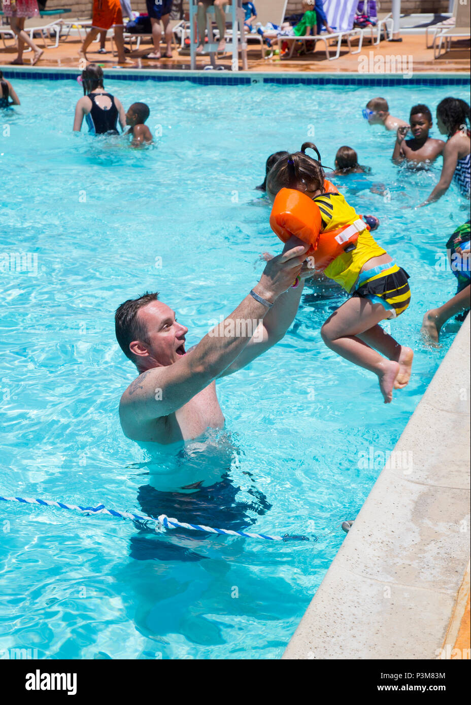 Army Chief Warrant Officer 2 Bryan Crumpler catches his daughter, Quinn,  age 2, as she leaps from the edge of the pool during the Marine Corps  Community Services All American BBQ at