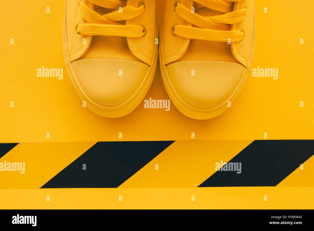 First in line young man queueing, conceptual overhead top view image of yellow sneakers waiting in line Stock Photo