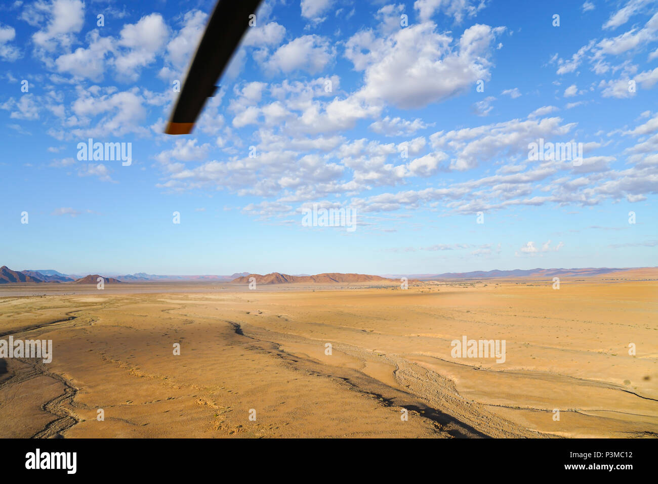 Aerial landscape, wide flat  area stretching to horizon with helicopter rotor blade  from tourist helicopter flight over Sossusvlei Namibia. Stock Photo